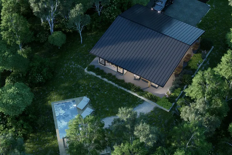 Vivienda de estilo contemporáneo con techo oscuro y piscina en terraza de madera, ubicada en un entorno natural rodeado de árboles.